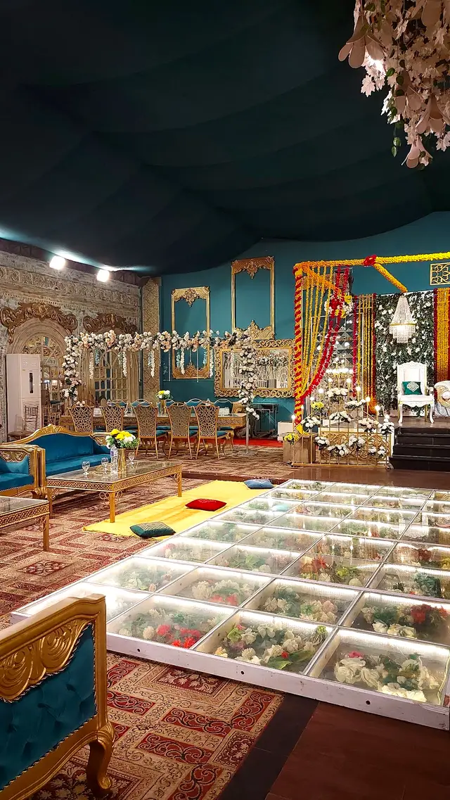 Teal hall set for a mehndi with a glass floor aisle